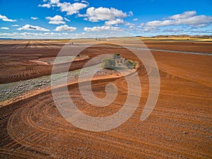 Plowed orange fields and old building ruins.