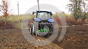 plowing in the field by a tractor with a trailed unit