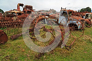Plows and vintage pickup trucks rusting in a scrapyard photo