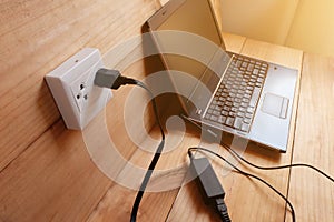 Plug in Adapter power cord charger of laptop computer On wooden floor