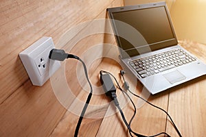 Plug in Adapter power cord charger of laptop computer On wooden floor