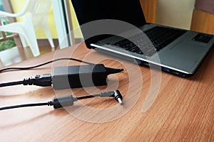 Plug in Adapter power cord charger of laptop computer On wooden photo