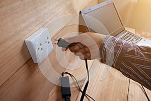 Plug in Adapter power cord charger of laptop computer On wooden floor