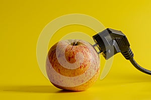 The plug gets energy from a fresh apple. Energy concept