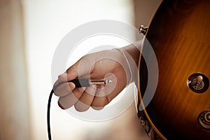 Plug jack cable in electric guitar,Hand inserts input jack to electric guitar