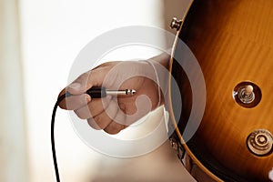 Plug jack cable in electric guitar,Hand inserts input jack to electric guitar