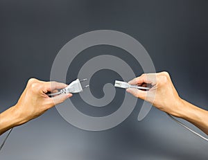 Plug and socket on hands holding on grey grey background