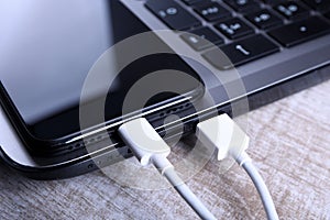 Plug in USB cord,cable charger,charging,charged and data transfer of the mobile phone,smartphone with a laptop on wooden floor,