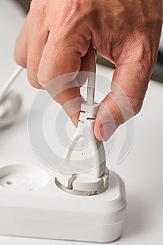 Plug in a white extension cord, male hand