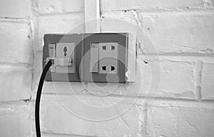 PLUGGED OLD SOCKET ON WHITE BRICK WALL