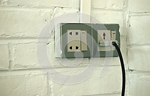 PLUGGED OLD SOCKET ON WHITE BRICK WALL