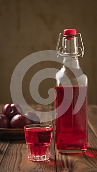 Plum alcoholic drink and plum berries on the rustic table. Flat lay.