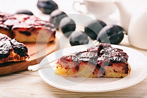 Plum bisquit cake on white wooden background. photo