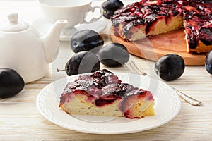 Plum bisquit cake on white wooden background.