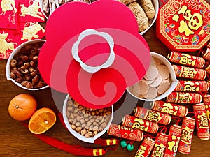 A plum blossom shaped candy box and the firecracker decorations on wooden brown background for the Ox year Lunar New Year.