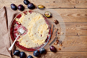 Plum crumble with aromatic spice on wooden rustic table top view. Autumn pastry.