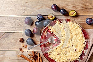Plum crumble with aromatic spice on wooden rustic table top view. Autumn pastry dessert.