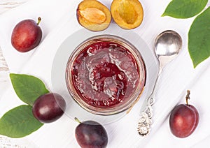 Plum jam in a jar, top view with fresh fruits