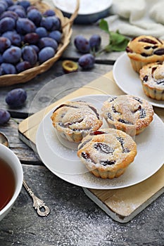 Plum muffins and cup of tea, powdered sugar dressing