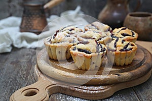 Plum muffins, powdered sugar dressing, cezve and cup of coffee