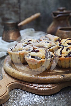 Plum muffins, powdered sugar dressing, cezve and cup of coffee