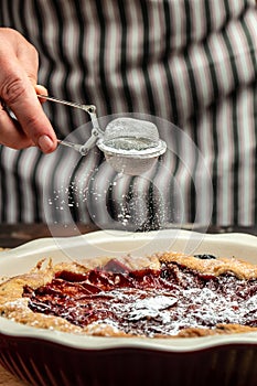 Plum pie powdered sugar is sprinkled on the cake. Cut pieces of pie on plate. Food recipe background. Close up