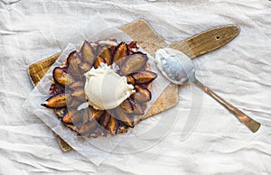 Plum pie with vanilla ice-cream ball on a wooden board