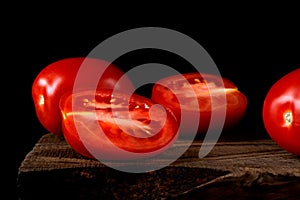 Plum tomato cut into halves on the old wooden board