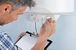 Plumber adjusting temperature of electric boiler photo