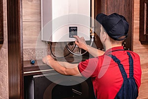 Plumber adjusts gas boiler before operating photo