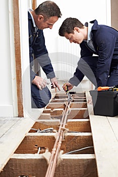 Plumber And Apprentice Fitting Central Heating in House