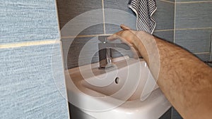 A plumber attaches a faucet to a basin. The hands of a plumber fixing a tap to a sink. Concept of small repairs in