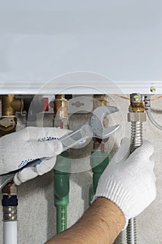 A plumber attaches to a gas pipe boiler with a wrench