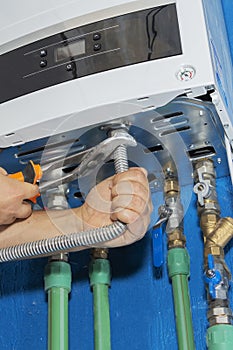 Plumber attaches to pipe gas boiler using adjustable wrench.