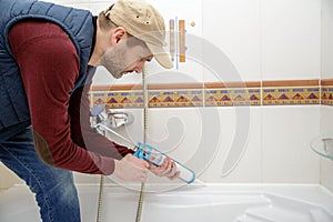 Plumber caulking bathtub.