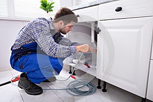 Plumber Cleaning Clogged Sink Pipe photo