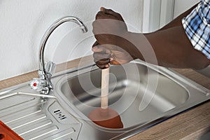 Plumber Cleaning Sink With Plunger