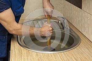 A plumber clear a blockage in a kitchen sink with a plunger