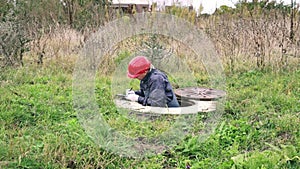 a plumber climbs out of a water well and records the water meter readings