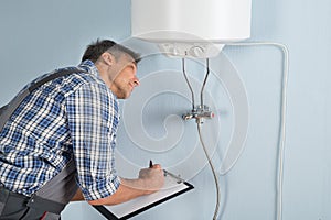 Plumber with clipboard looking at electric boiler