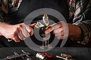 The plumber connects the brass fittings with an adjustable wrench. Closeup of a foreman is hands while working in a workshop