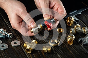 The plumber connects brass fittings to a plumbing faucet. Installation of gas equipment. Close-up of a master hand while working