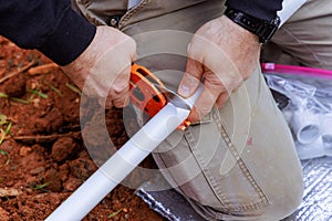 Plumber cuts plastic PVC pipe with a special pair of scissors
