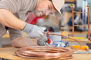 plumber cutting copper pipe with pipe cutter