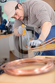 plumber cutting copper pipe with pipe cutter