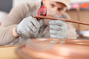 plumber cutting copper pipe with pipe cutter