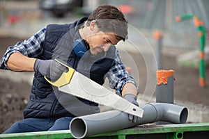 plumber cutting pvc pipe in house construction