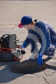 Plumber diagnoses a drain well on the street using special equipment