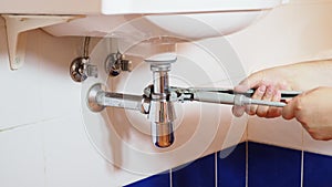 Plumber fixes adjustable plumber wrench on sink siphon
