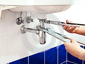 Plumber fixes pipe-wrenches to install a siphon